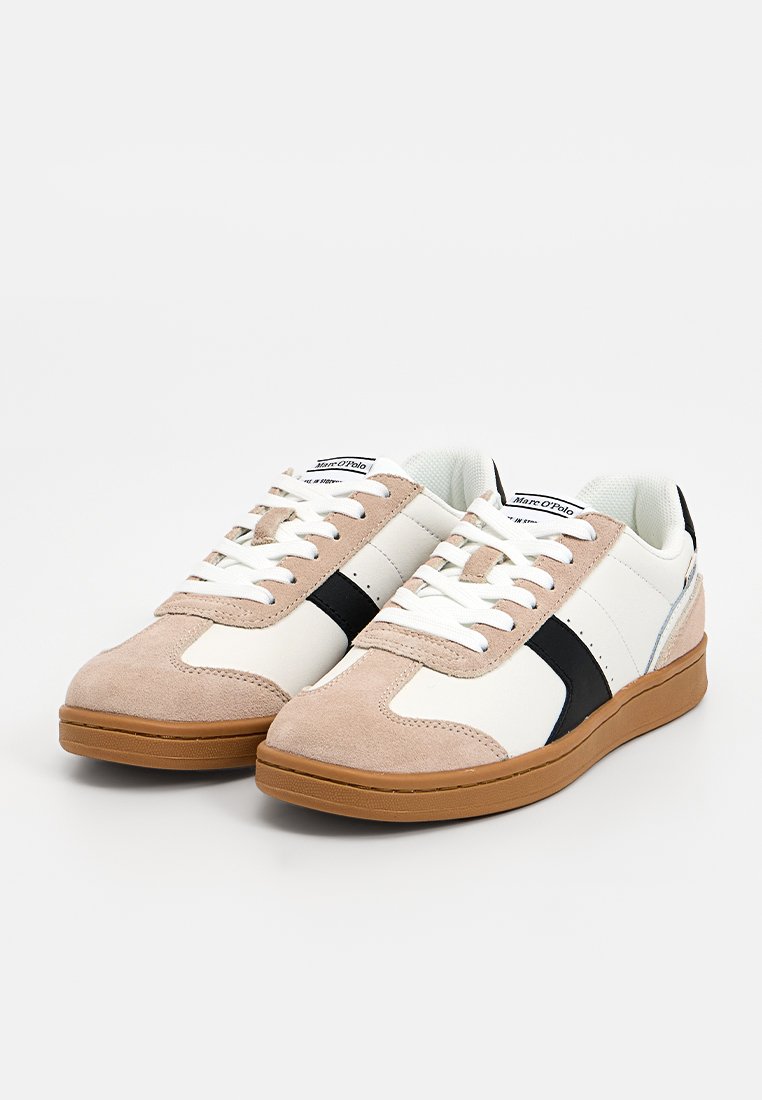 Ein Paar niedrige Sneaker aus beigem Wildleder, mit weißem Leder, schwarzem Streifen, weißen Schnürsenkeln und Gummisohlen.