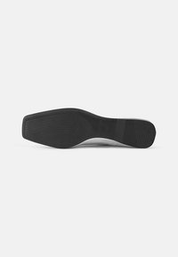 Black shoe sole with a flat, slightly curved shape. Features horizontal ridges for grip and a smooth, matte texture on the sides.