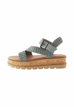 Woven light blue sandal with ankle strap and buckle, featuring a cork platform and a textured sole for added grip and comfort.