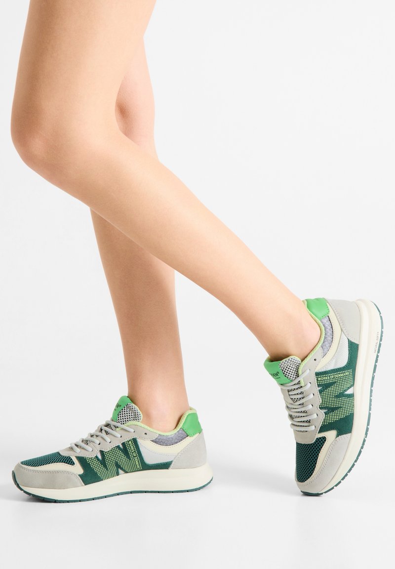 Groen- en grijsgekleurde sneakers van mesh en suède, met een patroonlaag, gestructureerde tong en een witte rubberen zool met een groene accentkleur.