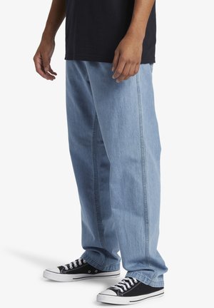 Lyseblå denimjeans med en løs pasform, der har lige ben og synlige stikninger. Kombineret med sorte høj-top sneakers.