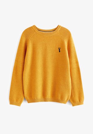 Maglione giallo senape lavorato a maglia con spalle e polsini a coste, con un piccolo emblema a forma di testa di cervo blu navy sul petto sinistro.