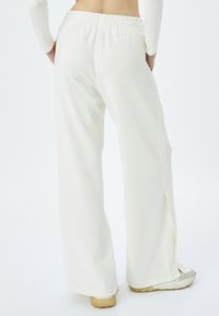 Witte, loszittende broek met een elastische tailleband, met zijsplitten aan de onderkant. Zachte stof en recht model.