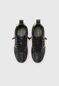 Baskets noires en cuir avec un design texturé, des accents dorés et des lacets noirs ; elles possèdent une languette et un intérieur rembourré.