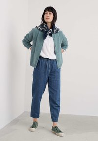 Kerge roheline kudumiskardigan nööbiga, valge pluus, vabaja sinised teksap�üksid ja rohelised tossud. Sall, millel on tumesinine ja valge muster.