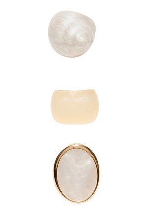 Tre forskellige creme- og hvid-marmorering ringe med glatte, blanke overflader, arrangeret vertikalt på en hvid baggrund.