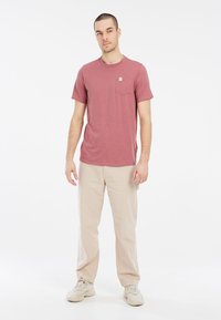 Tričko s krátkym rukávom, mierne textúrované, vyblednuté maliny, s vreckom na hrudi; v kombinácii s béžovými voľnými nohavicami a svetlými teniskami.