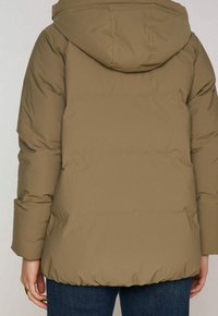 Zimní bunda v olivově zelené barvě s kapucí, která má hladký povrch a elastické manžety. Silueta je uvolněná a mírně prostorná.