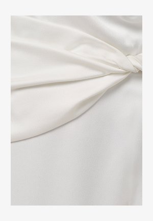 Hladká biela saténová látka s detailom skrúteného uzla vytvára jemné záhyby a jemný lesk.