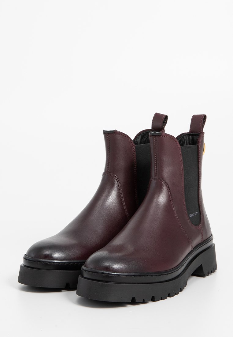 Botas Chelsea de cuero burdeos con paneles laterales elásticos, punta redonda, suela de goma negra gruesa y lengüetas para facilitarlas poner.