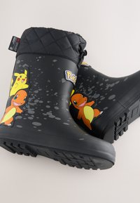 Schwarze wasserdichte Stiefel mit gesteppter Manschette, die die Pokémon-Charaktere Pikachu und Charmander sowie das Pokémon-Logo an den Seiten zeigen.