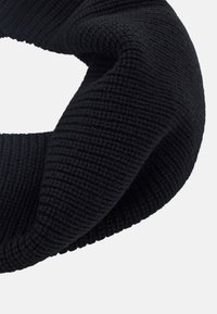 Fascia per la testa nera lavorata a maglia con una texture a costine, forma circolare e tessuto morbido. Il design è senza soluzione di continuità, senza hardware visibile o accenti.