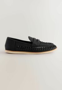 Mocassins en cuir noir avec un design tissé sur le dessus, style slip-on, et une semelle en caoutchouc beige. Texture plate et lisse sur l'ensemble.