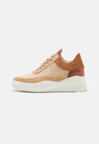 Sneaker en daim beige et marron avec des lacets beige clair, semelle épaisse blanche et design à panneaux superposés, vue depuis le côté extérieur.