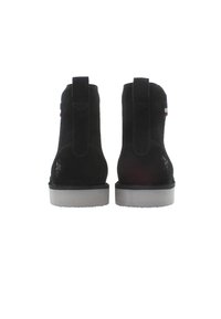 Botines de ante negro con una textura suave, suela gris plana y una lengüeta en la parte trasera. Presentan un pequeño acento tricolor.