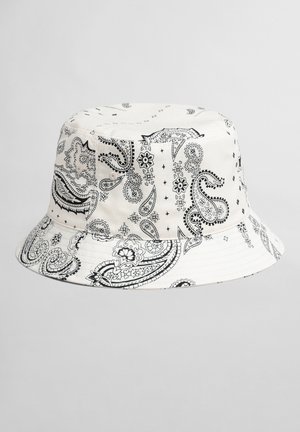 Biały kapelusz typu bucket z czarnymi, misternymi wzorami paisley i kwiatowymi równomiernie rozmieszczonymi na tkaninie.