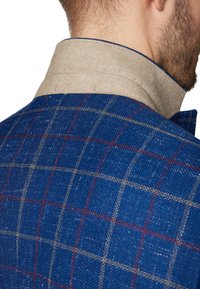 Niebieska tkanina w kratkę z jasnobeżowym filcowym kołnierzykiem. Wzór zawiera cienkie linie w kolorze czerwonym i białym, co nadaje mu wyraźną fakturę i detale.