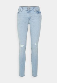 Jeans skinny de mezclilla azul claro con cintura de altura media, que presentan detalles desgastados, cinco bolsillos y un cierre clásico de botones y cremallera.