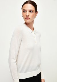 Lichtcrème, langharige polo trui met een kraag, knoopsluiting aan de voorkant en geribbelde zoom. Gemaakt van zachte, gestructureerde stof.