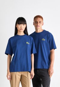 Camisetas de algodón azul marino con mangas cortas y cuello redondo, que cuentan con un pequeño logo de cocodrilo verde en el pecho.
