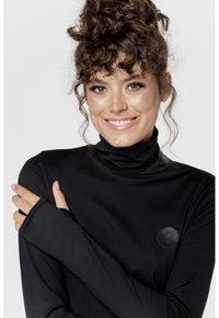 Czarny longsleeve z golfem wykonany z gładkiego materiału, z okrągłą skórzaną naszywką z logo na lewej piersi i otworami na kciuki w rękawach.