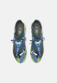 Scarpe sportive con tomaia in mesh blu e dettagli verdi, linee e pattern intricati, e suola testurizzata. Progettate per le prestazioni.