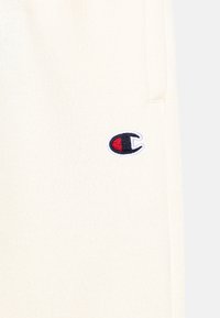 Kermanhuppari, jossa on tekstuuri. Vasemmassa rinnassa on pieni sinivalkoinen ja punainen brodeerattu logo.