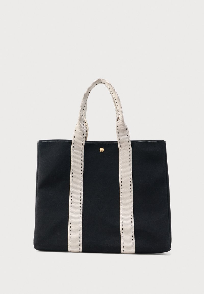 Μαύρη τσάντα tote με δύο φαρδιές μπεζ λαβές ραμμένες με μαύρο νήμα, που διαθέτει ένα μικρό χρυσό κουμπί κοντά στο κέντρο στην κορυφή.