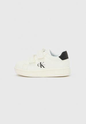 Białe dziecięce trampki z czarnym detalem na pięcie, paskami na rzep i logo Calvin Klein po boku, pokazane na jednolitym jasnym tle.