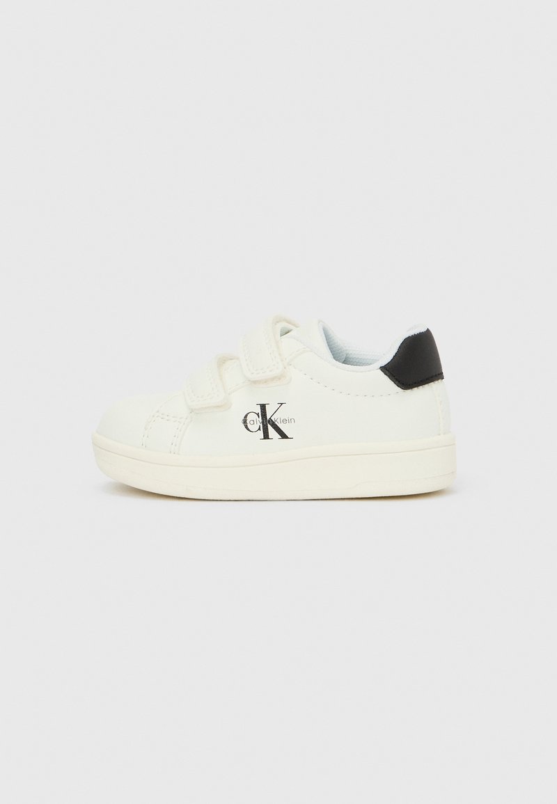 Baskets blanches pour enfants avec détail talon noir, brides en velcro et logo Calvin Klein sur le côté, présentées sur un fond clair uni.