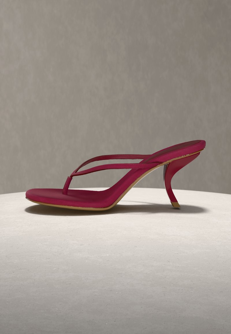 Sandale à talon rouge avec design à lanières et talon stiletto incurvé, présentée sur une surface ronde blanche contre un fond gris clair.