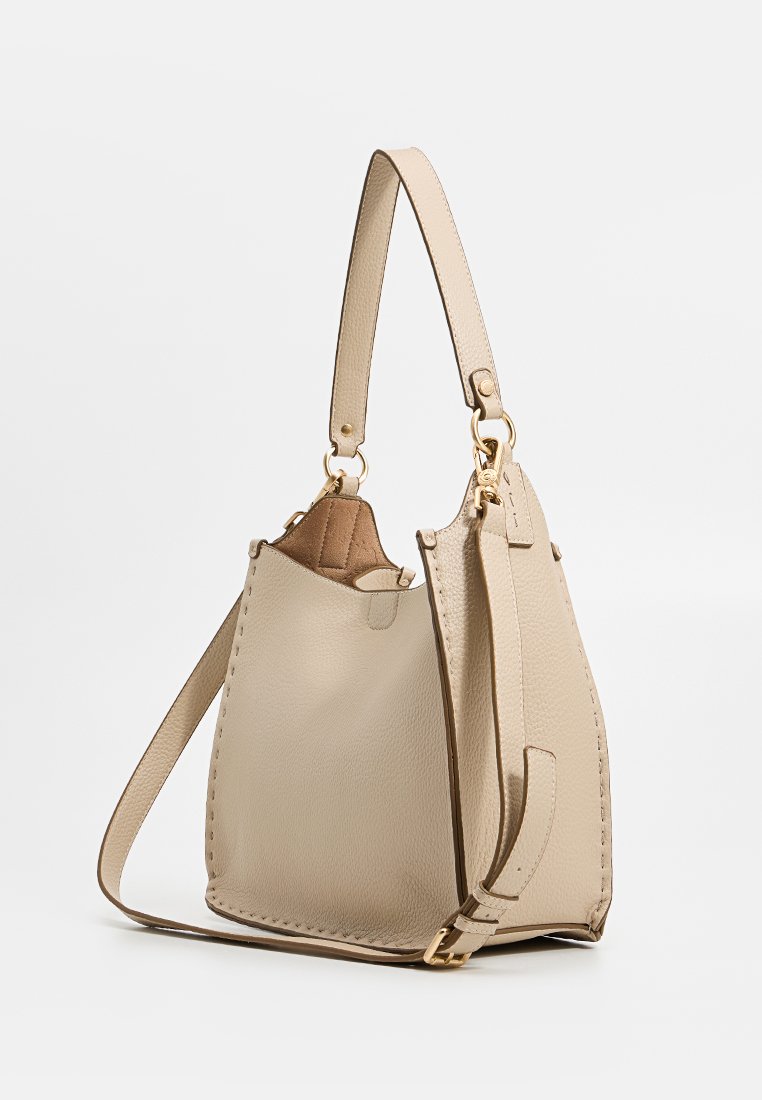 Borsa a mano in pelle beige con forma strutturata, caratterizzata da un accento in hardware dorato e una tracolla removibile. Dettagli di cucitura lungo i bordi.