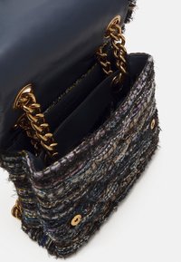 Tweedová kabelka s vícebarevným strukturovaným vnějškem. Má tmavý kožený interiér, zlaté řetízkové detaily a magnetické zapínání.
