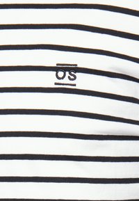 Hvid bomulds t-shirt med marineblå vandrette striber, der har et lille broderet logo "OS" nær halsudskæringen. Blød tekstur og tætsiddende design.