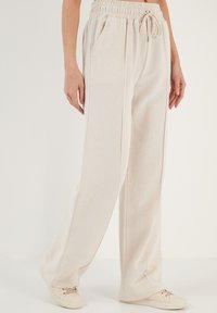 Beige katoenen wijde broek met een elastieken tailleband en koord. Voorzien van zijzakken en een zachte, gestructureerde stof.