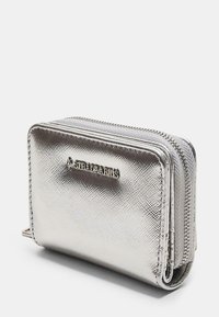 Metaliczny srebrny portfel z zamkiem błyskawicznym, z teksturowaną powierzchnią i akcentem z logo z przodu. Kompaktowy prostokątny kształt.