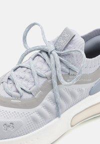 Light gray athletic shoe with a textured knit upper, gray accents, a padded collar, rounded toe, and a white rubber sole. Laces are tied securely.