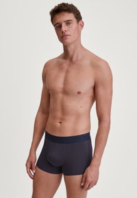 Boxer da uomo in tessuto grigio scuro con una texture liscia e cintura elastica con il nome del marchio "CALIDA."