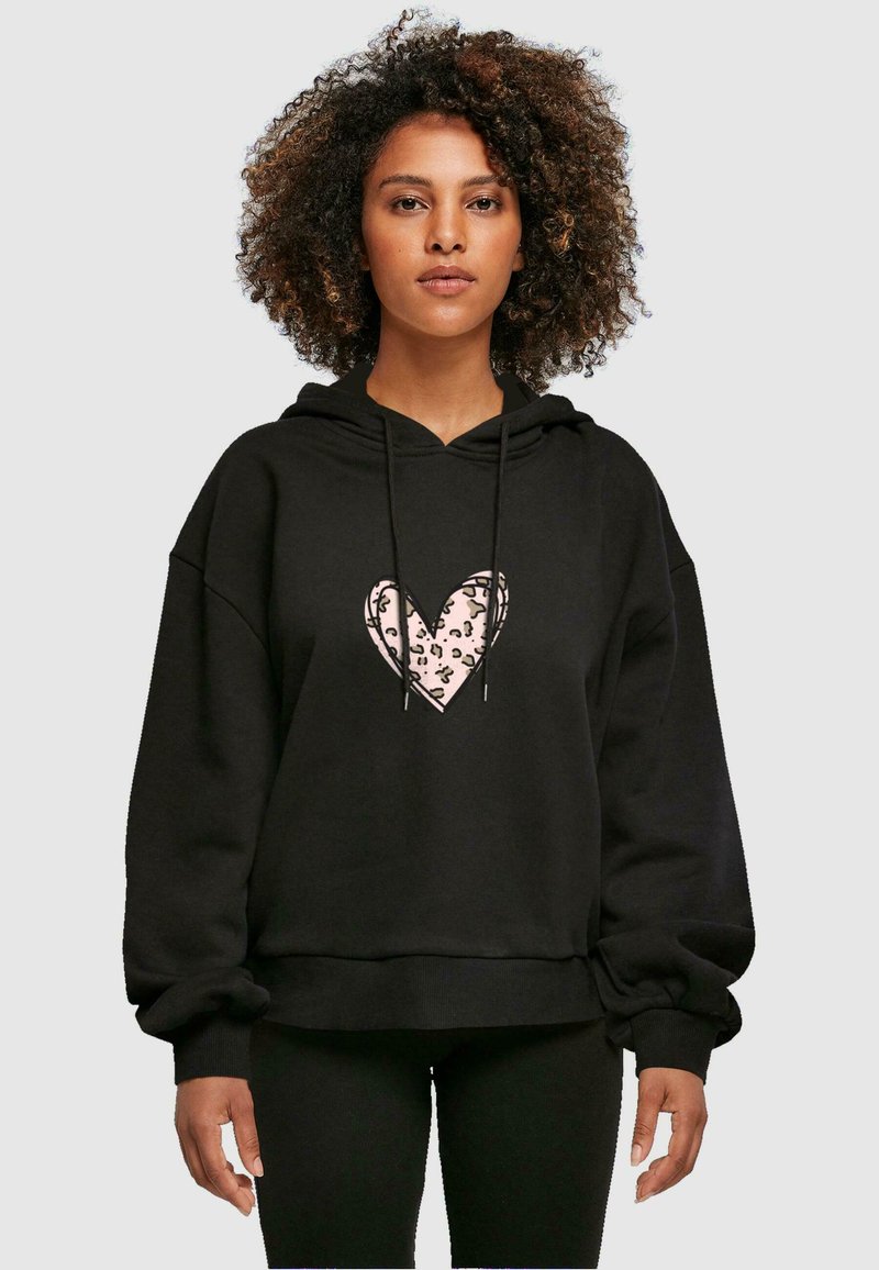 Hoodie noir avec un grand motif de cœur rose à motif léopard. Coupe oversize avec capuche à cordon de serrage et poignets côtelés.