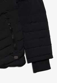 Černá péřová bunda s prošívanou texturou, zipovou kapsou na levém rukávu a žebrovanými úplety na koncích rukávů.