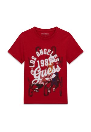 T-shirt rouge à manches courtes avec le texte "Los Angeles 1981 Guess" et un graphisme de trois joueurs de basketball en action sur le devant.
