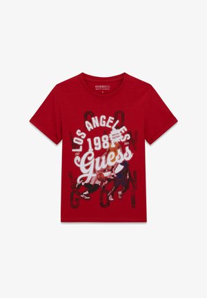 T-shirt rouge à manches courtes avec le texte "Los Angeles 1981 Guess" et un graphisme de trois joueurs de basketball en action sur le devant.