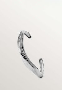Brazalete de cuff de metal plata con un diseño suave y ondulado y extremos redondeados, que presenta una superficie reflectante y sin cierres visibles.
