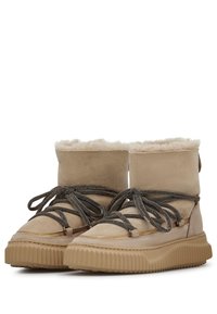 Botas de tobillo de ante beige con forro de piel, suela de goma texturizada y cordones oscuros; cuenta con un caño alto y plegable para ajustar la altura.