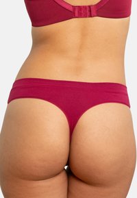 Burgunderfarbene Baumwollthong mit nahtlosem Design, weichem Material und minimalem elastischen Bund, der einen tiefen Schnitt präsentiert.
