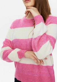 Rozā un baltu svītru džemperis ar apaļu kakla izgriezumu un ribām piedurknēm. Mīksta tekstūra, kas piedāvā košus krāsu blokus un brīvu piegriezumu.