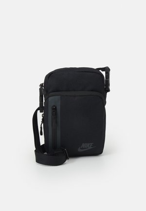 Petit sac bandoulière noir Nike avec sangle réglable, poche avant zippée et compartiment principal zippé sur fond blanc.