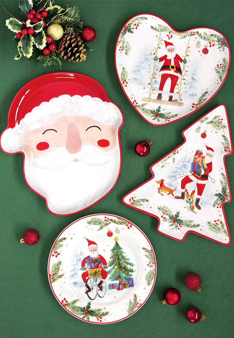 Weihnachtsteller im Santa-Thema in Form von Santas Gesicht, Herz, Baum und rund mit Feiertagsszenen, umgeben von roten Ornamenten und Grünpflanzen.