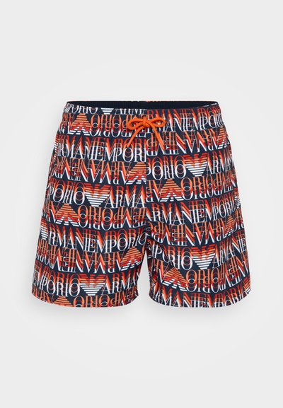 Simshorts med ett flerfärgat mönster av logotyper i rött, vitt och blått. Materialet är lätt med elastisk midja och snörning.