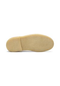 Semelle d'une chaussure, en caoutchouc beige clair, présentant une surface lisse, une forme arrondie et une légère courbure au niveau du talon.
